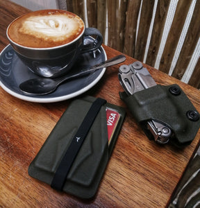 durable leatherman pouch and olive drab minimalist card holder next to cup of coffee